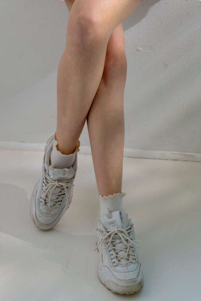 services-02 Artistic minimalist photo of legs crossed wearing white sneakers, with warm shadows.